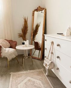 a white table and chair in a room with a large mirror on the wall above it