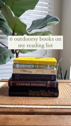 a stack of books sitting on top of a table next to a potted plant