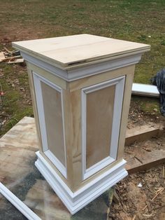 an unfinished cabinet sitting on top of a piece of wood in the middle of a yard