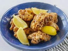 a blue plate topped with fried chicken and lemon wedges