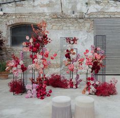 a bunch of flowers that are on some kind of stand in front of a building