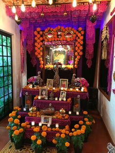 the altar is decorated with flowers, candles and pictures in front of an ornate mirror