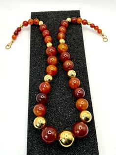 Description: I created this necklace using beautiful, vintage Bakelite (tested) beads along with gold-tone ball findings harvested from a vintage necklace.  There are 32 beautiful beads that graduate in size. The honey/cherry color beads have translucency.  The End-of-the-Day striations are mesmerizing.  The necklace is strung on two-strand, red silk string. Its gold, lobster-claw clasp is signed 14 karat gold-filled.  Even more pretty than the photos.  Enjoy! (*All my Bakelite is authenticated using Simichrome Polish.) * * * * * NECKLACE: 21" Vintage Bead measurements: largest ~18 mm; smallest ~6 mm Total Necklace Wt.: ~75 gms Total vintage bead count: 32 Hallmark(s): the lobster-claw clasp is stamped "GF" & "14/20" Condition: Excellent. Beads are shiny & healthy.  Superficial wear on cla Formal Gold Beaded Necklaces, Classic Gold Necklace With Gemstone Beads, Gold Beaded Necklaces With Round Beads For Formal Occasions, Formal Necklace With Round Gold Beads, Formal Gold Hand-strung Beaded Necklaces, Formal Costume Jewelry Necklace With Round Beads, Formal Costume Jewelry With Round Beads Necklace, Vintage Round Bead Necklaces Collectible, Classic Gold Hand-strung Necklace