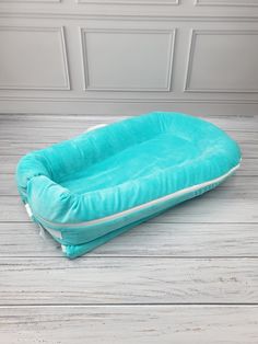 a blue dog bed sitting on top of a wooden floor next to a white wall