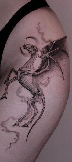 a woman's thigh with a tattoo design on it, depicting a winged dragon