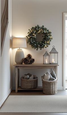 a christmas wreath on the wall above a table with two baskets and candles next to it