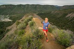 a woman running down a trail in the mountains