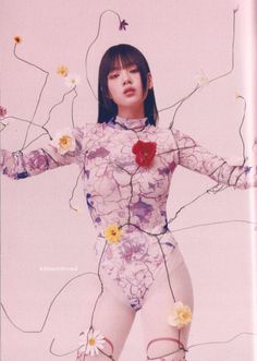 a woman in a bodysuit with flowers on her chest and arms stretched out to the side