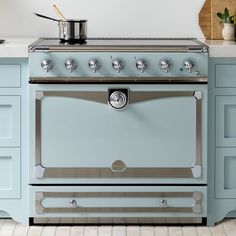 a blue stove top oven sitting inside of a kitchen next to counter tops and drawers