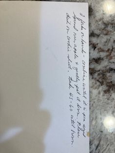 a piece of paper with writing on it sitting on a counter top next to a cell phone