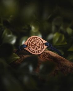 a wooden bracelet with an engraved compass on it sitting on top of a tree branch