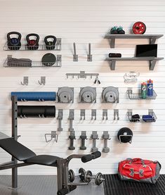 a gym room with various exercise equipment on the wall and in front of it is a red duffel bag