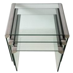 a glass table with metal legs and two shelves on each side, against a white background