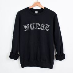 a black sweatshirt with the word nurse on it hanging from a hanger against a white wall