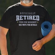 a man holding a blue yoga mat in his right hand and wearing a black t - shirt that says, officially retired under new management see wife for details