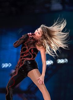 a woman is performing on stage with her hair blowing in the wind