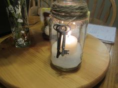 a mason jar filled with sand and a lit candle sitting on top of a wooden table