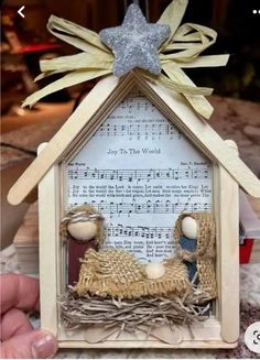 a nativity scene made out of wood with sheet music and stars on the top