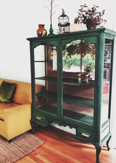 a green cabinet sitting on top of a hard wood floor next to a yellow couch