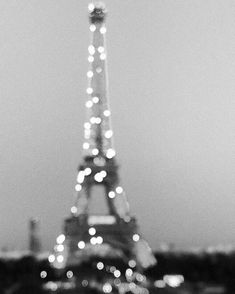 the eiffel tower lit up at night in black and white with blurry lights