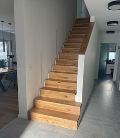 there is a wooden stair case in the house with white walls and wood steps leading up to the second floor