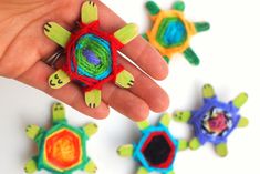 a hand is holding some colorful toys in the shape of turtles and tortoises