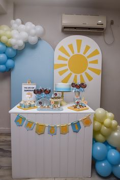 a birthday party with balloons and decorations on the side of a table in front of a wall