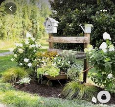 a garden filled with lots of flowers and plants next to a wooden bench in the grass