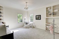 a bedroom with white walls and carpeted flooring has a chandelier hanging from the ceiling