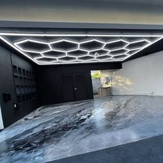 an empty room with black walls and flooring, lights on the ceiling are shining