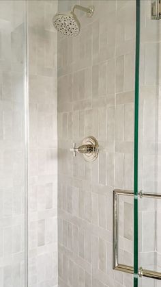 a white tiled shower with thermostaer and hand held shower faucet