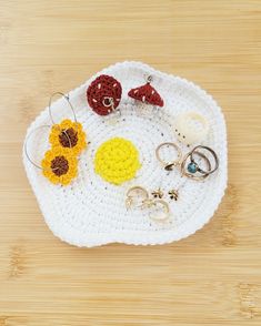 a crocheted tray with rings and flowers on it