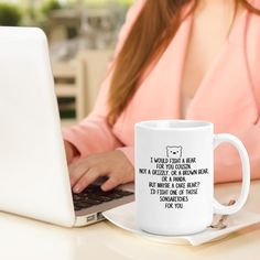 a woman is typing on her laptop while sitting at a table with a coffee mug in front of her