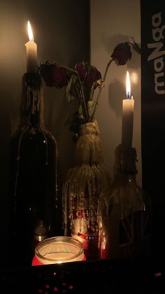 candles and bottles with flowers in them on a shelf next to a candlelight holder