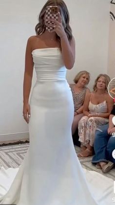 a woman in a white wedding dress is taking a selfie with her cell phone