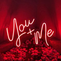 a red neon sign that says you and me in the middle of some rocks under it