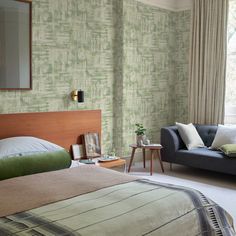 a bed room with a neatly made bed next to a couch and table in front of a window