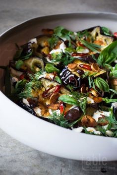 a white bowl filled with lots of food on top of a table