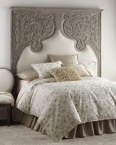 an ornate headboard in a bedroom next to a bed with pillows and blankets on it