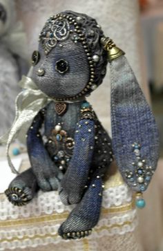 a small stuffed animal sitting on top of a piece of cloth with beads and pearls