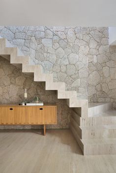 a wooden cabinet sitting in the middle of a room next to a stone stair case