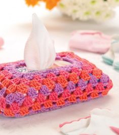 a tissue dispenser sitting on top of a table with crocheted cloths