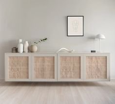 a white and beige sideboard sitting on top of a wooden floor next to a lamp