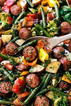 sausage and veggies in a skillet with a wooden spoon