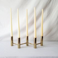 four candles are lined up next to each other on a white tablecloth covered surface