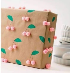 a brown paper bag with pink pom - poms and green leaves on it