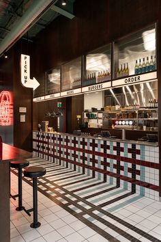 the inside of a fast food restaurant with checkered flooring and red neon signs