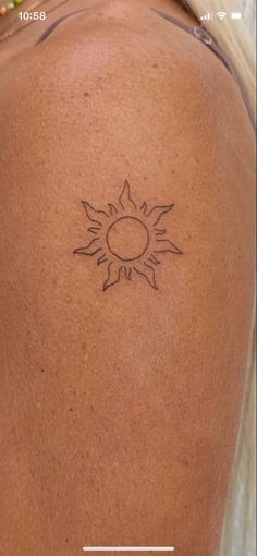 the back of a woman's shoulder with a sun tattoo on it