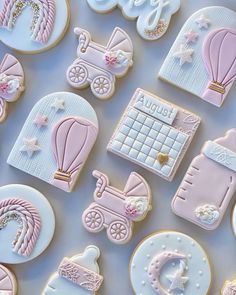 baby shower cookies with pink and white icing on a blue tablecloth next to other decorated cookies