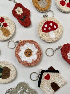 crocheted keychains are arranged on a white tablecloth with red flowers